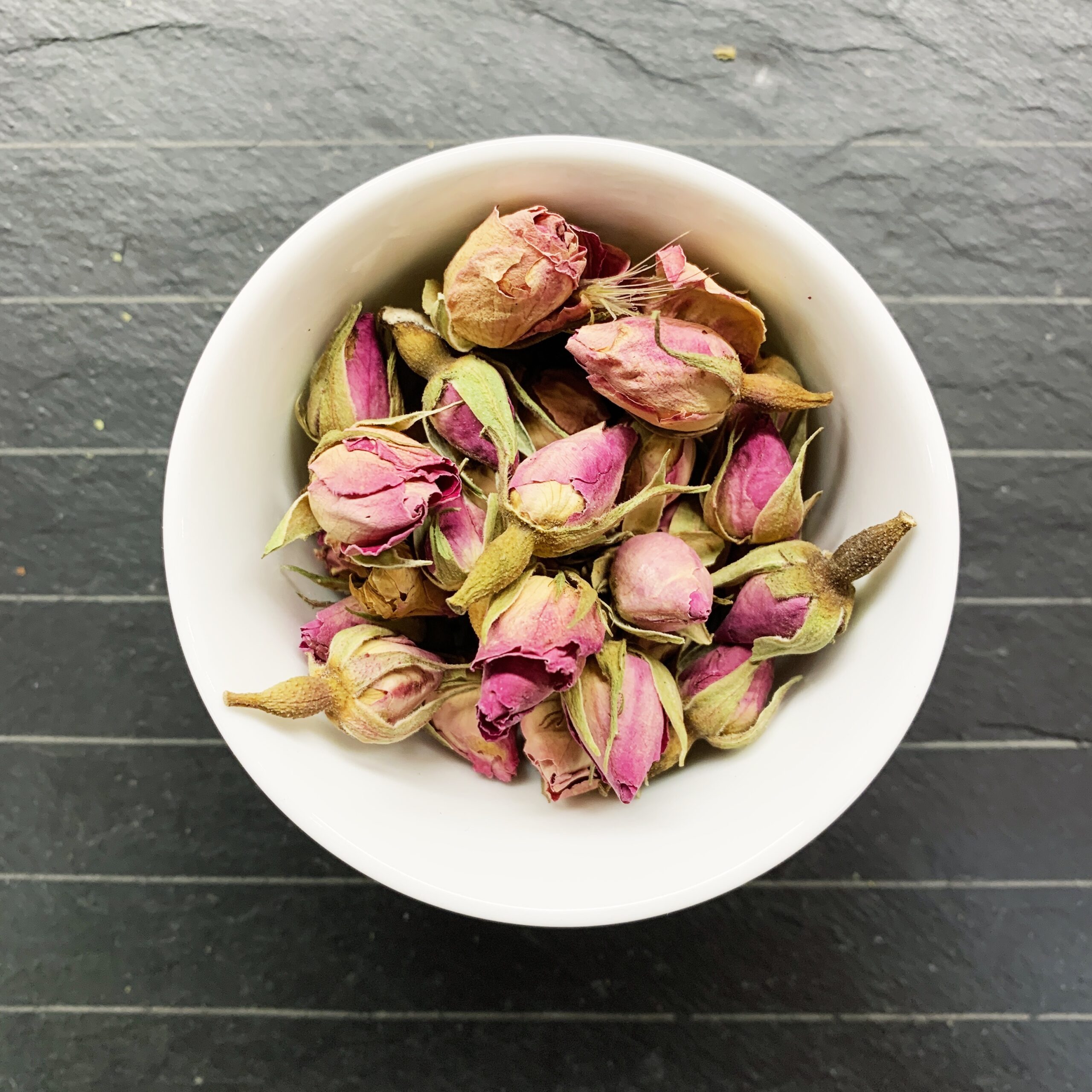 Boccioli di rosa secchi organici in mano maschile su sfondo di legno.  Concetto di aromaterapia. Boccioli di rosa essiccati per cosmetici, cibo,  medicina e profumo. Chiudi Foto stock - Alamy